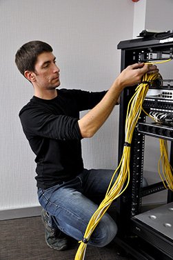 Фото мужчина укладывает кабель в шкаф