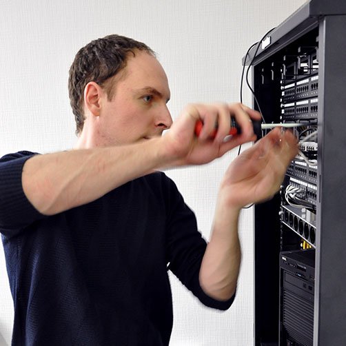 Фото мужчина с отверткой в руках обслуживает серверное оборудование