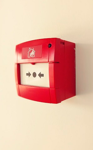 Красная кнопка пожарной сигнализации на стене