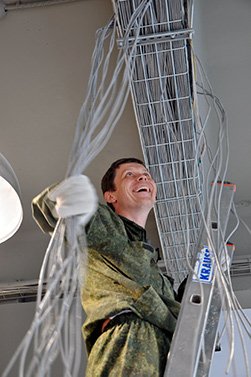 Мужчина на лестнице монтирует потолочные кабели